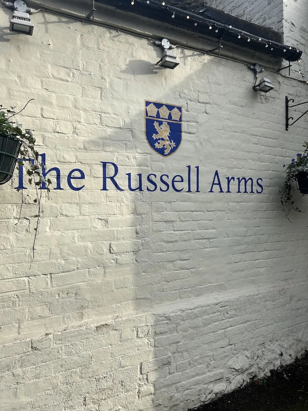 The Russell Arms crest and wordmark painted on the pub's white brick exterior
